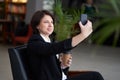 Portrait of young caucasian business woman wearing black suit doing selfie on the phone while coffee break Royalty Free Stock Photo