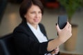 Portrait of young caucasian business woman wearing black suit doing selfie on the phone while coffee break Royalty Free Stock Photo