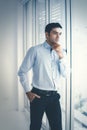 Portrait of young Caucasian businessman standing sad near a window in the office. Stressed and worried about the economic downturn Royalty Free Stock Photo