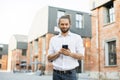 Portrait of young caucasian businessman using mobile phone in city. Royalty Free Stock Photo