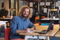 Portrait of young caucasian businessman writing in diary at desk in creative office Royalty Free Stock Photo