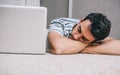 Portrait of young Caucasian freelancer business man sleeping near to laptop with eyes closed while lying on the floor home. Quick Royalty Free Stock Photo