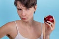 Portrait of a young Caucasian girl who bites off red Apple and looks at the camera Royalty Free Stock Photo