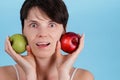 Portrait of young Caucasian girl who holds a red and green Apple in her hands as a concept of choosing the right food Royalty Free Stock Photo