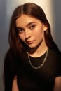 portrait of young caucasian lady with long hair, metal shiny chain in black top