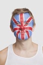 Portrait of young Caucasian man with British flag painted on face against white background Royalty Free Stock Photo