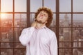 Portrait of a young caucasian man with curly hair having a neckache.