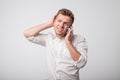 Portrait of young caucasian uncertain man using mobile phone on gray background. Royalty Free Stock Photo