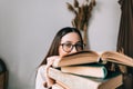 Portrait of young caucasian woman college student in eyeglasses hiding behind a book and looking at camera Royalty Free Stock Photo