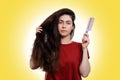 Portrait of a young caucasian woman holding her thick dark hair and comb for combing. White background. Hair care concept