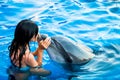 Portrait of young Caucasian woman kiss dolphin in pool water of Batumi delphinarium. Swim with dolphin experience concept Royalty Free Stock Photo