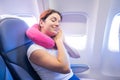 Portrait of a young caucasian woman on a plane with a travel pillow around her neck