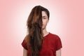 Portrait of a young Caucasian woman with a ponytail covering half of her face. Pink background. The concept of unruly hair and its