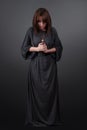 Portrait of a young caucasian woman praying. Prayer girl dressed in Vestments of a nun on gray studio background Royalty Free Stock Photo