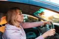 Portrait of young caucasian woman is sitting at the wheel of a right-handed car and anxiously looks at the road. Traffic