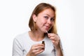 Portrait of a young caucasian woman smearing medicine on a pimple on her chin. White background. Acne and pimples