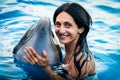 Portrait of young Caucasian woman smile with dolphin look to camera in pool water of Batumi delphinarium. Swim with dolphin Royalty Free Stock Photo