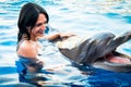 Portrait of young Caucasian woman smile with dolphin in pool water of Batumi delphinarium. Swim with dolphin experience concept