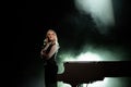 Portrait of young caucasian woman standing near the grand piano in the beam of light Royalty Free Stock Photo