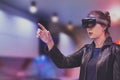 Portrait of young Caucasian woman using augmented and virtual reality with holographic hololens glasses. Pink, magenta and blue