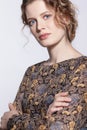 Portrait of a young caucasian woman in vintage retro dress and wavy hair on a gray background