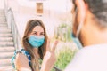 Portrait of a young Caucasian woman making a sign of contempt with her fingers to a young man with a mask Royalty Free Stock Photo