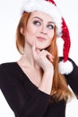 Portrait of a young charming red-haired girl in a shiny Christmas hat.