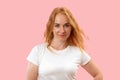 Portrait of young charming redhead woman with long wavy hair in white t shirt, pink background. Beautiful confident woman Royalty Free Stock Photo
