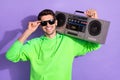 Portrait of young cheerful attractive cool student guy smiling touch specs hold boombox listen loud music disco isolated Royalty Free Stock Photo