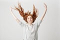 Portrait of young cheerful beautiful redhead girl smiling with closed eyes shaking hair over white background. Royalty Free Stock Photo