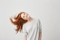 Portrait of young cheerful beautiful redhead girl smiling with closed eyes shaking head and hair over white background. Royalty Free Stock Photo