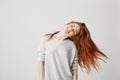 Portrait of young cheerful beautiful redhead girl smiling with closed eyes shaking head and hair over white background. Royalty Free Stock Photo