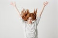 Portrait of young cheerful beautiful redhead girl smiling looking at camera shaking hair over white background. Royalty Free Stock Photo