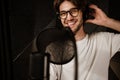 Portrait of young cheerful male singer in headphones happily looking in camera recording new song in studio Royalty Free Stock Photo