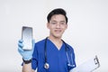 Portrait of a young and cheerful medical student, intern, nurse holding a phone. Isolated on a white background Royalty Free Stock Photo