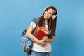 Portrait of young cheerful pleasant woman student in denim clothes with backpack headphones listening music, hold school Royalty Free Stock Photo