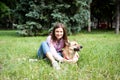 Portrait of a young cheerful woman sitting in the park on the green grass with a dog from the shelter. Royalty Free Stock Photo