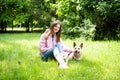 Portrait of a young cheerful woman sitting in the park on the green grass with a dog from the shelter. Royalty Free Stock Photo