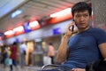 Portrait of young Asian man talking on the phone and sitting at the subway station Royalty Free Stock Photo