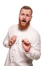 Portrait of a young, chubby, redheaded man in a white shirt making faces at the camera, isolated on a white background Royalty Free Stock Photo