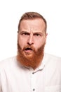 Portrait of a young, chubby, redheaded man in a white shirt making faces at the camera, isolated on a white background Royalty Free Stock Photo