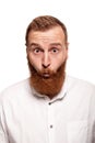 Portrait of a young, chubby, redheaded man in a white shirt making faces at the camera, isolated on a white background Royalty Free Stock Photo