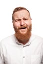 Portrait of a young, chubby, redheaded man in a white shirt making faces at the camera, isolated on a white background Royalty Free Stock Photo