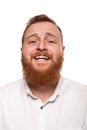 Portrait of a young, chubby, redheaded man in a white shirt making faces at the camera, isolated on a white background Royalty Free Stock Photo