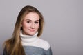 Portrait of a young classy girl with blond long hair and brown eyes on a gray background