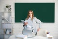 Portrait of young clever smart female college student studying in classroom on class with blackboard background. Royalty Free Stock Photo