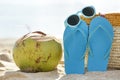 Young coconut, flipflops, and sunglasses on the sand