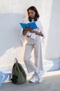 Portrait of a young college girl reading a book near the wall. The student is smiling and happy Royalty Free Stock Photo