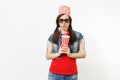 Portrait of young concerned pretty woman in 3d glasses with bucket for popcorn on head watching movie film and holding