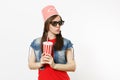 Portrait of young concerned pretty woman in 3d glasses with bucket for popcorn on head watching movie film and holding